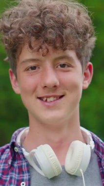 Dikey video. Kulaklıkla dans eden mutlu genç kızın portresi..