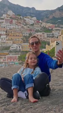  Bir anne ve küçük kızı, İtalya 'nın Amalfi Sahili' ndeki Positano sahilinde otururken selfie ve fotoğraf çekiyorlar. İtalya.