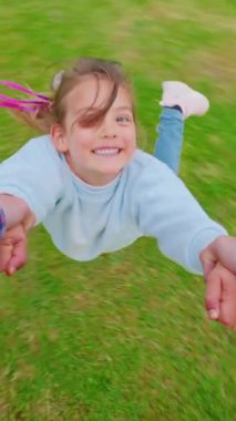 Küçük bir kızın kolları ve babası tarafından döndürüldüğünü gösteren bir bakış açısı..