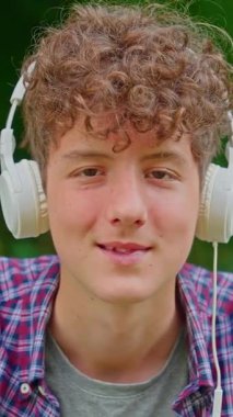 Dikey video. Kulaklıkla dans eden mutlu genç kızın portresi..