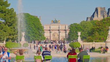 Tuileries Garden, Paris, Fransa, 30.05.2025. İnsanlar parkta yürüyor ve çeşmenin yanındaki sandalyelerde oturuyorlar..