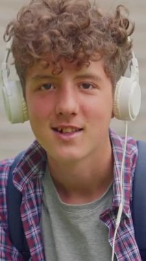 Dikey video. Kulaklıkla dans eden mutlu genç kızın portresi..