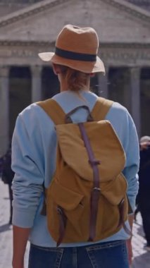 Şapkalı ve sırt çantalı bir turist kız eski Roma şehrinin etrafında ünlü antik Pantheon 'un yanında ve yakınındaki meydanda yürüyor. Pantheon cephesi. Roma, İtalya, 12.04.2025.