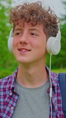 Dikey video. Kulaklıkla dans eden mutlu genç kızın portresi..