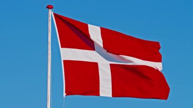 Rüzgarda dalgalanan Danimarka bayrağı, rüzgarda mavi gökyüzünün arka planına karşı.