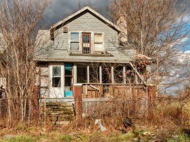 An abandoned house in Highland Park is being overcome by plants and bushes.