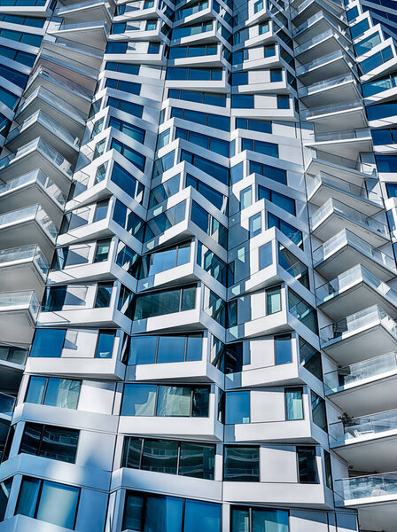 Солнечный свет подчеркивает контраст между светом и тенью на фасаде современного многоквартирного дома.