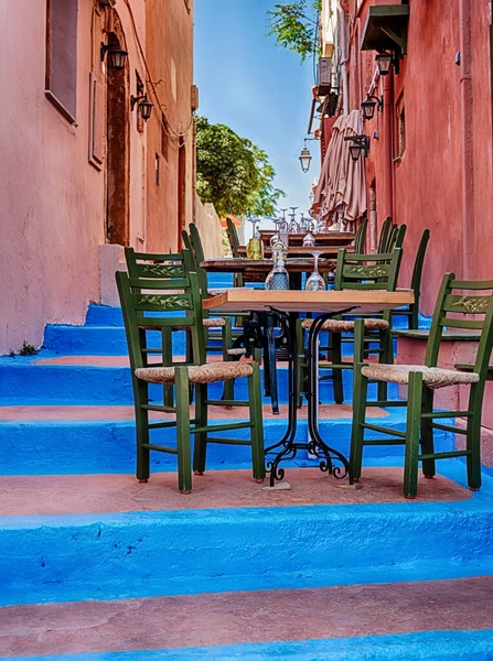 A small cafe is located in an alley with blue relief on the steps in Rethymno, Crete.