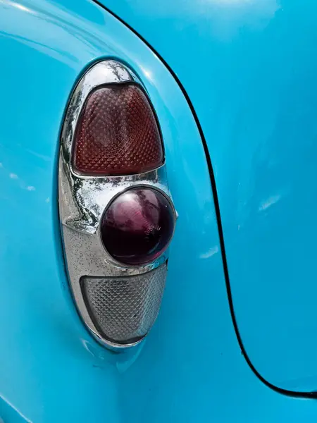 A powder blue classic American car with a red tail light detail and the lines of the trunk opening is parked outdoors on the streets of Lima, Peru.