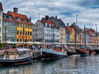 Danimarka 'nın başkenti Kopenhag' daki Nyhavn Kanalı 'nın tarihi turistik durağı tekneler ve dükkanlar hizasında..