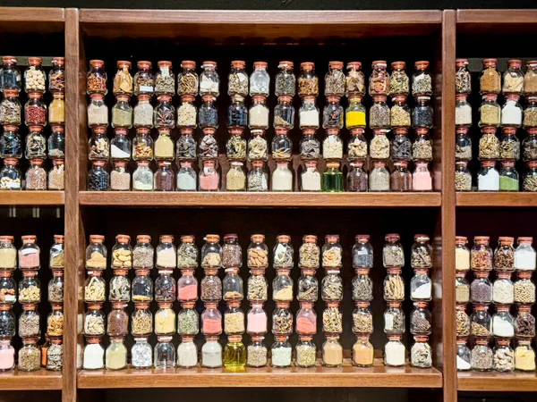 Several wooden shelves are stacked full of different glass spice jars filled with multi-colored spices and flavors in central Lima.