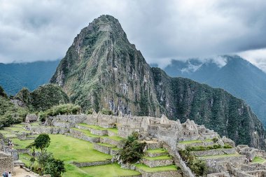 Machu Picchu 'nun sözde kraliyet sarayının kartpostal görüntüsü Huayna Picchu dağı ve arkaplanda bulutlar.