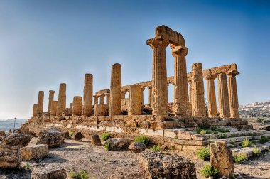 The ancient ruins of the Temple of Juno is illuminated by the sunlight in the late afternoon at the Valley Of The Temples near Agrigento on Sicily. clipart