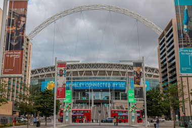 Londra, İngiltere - 13 Temmuz 2023: Wembley Stadyumu önünde iki kırmızı çift katlı otobüs ve arka planda kara fırtınalı gökyüzü.