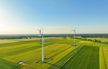 Rüzgar enerjili türbinlerin hava aracı görüntüsü, bir rüzgar çiftliğinin parçası. Kırsal bölgedeki yeşil alanda rüzgar türbinleri. Rüzgar santrali.
