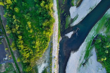 Ormanın ortasında kayalık bir nehir. Gökyüzünü yansıtan sakin nehrin havadan görünüşü, yemyeşil bir manzara, hava manzarası. Ormandaki bir dağ nehri manzarası.