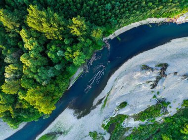 Ormanın ortasında kayalık bir nehir. Gökyüzünü yansıtan sakin nehrin havadan görünüşü, yemyeşil bir manzara, hava manzarası. Ormandaki bir dağ nehri manzarası.
