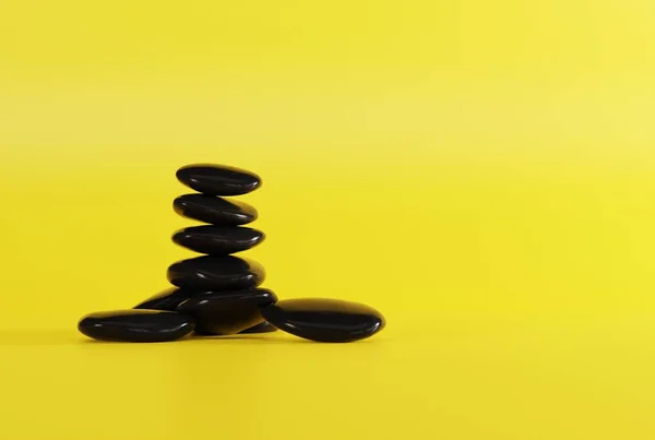 黄色背景上的黑色按摩石 按摩的概念 Spa和美容护理 3D渲染 3D插图 — 图库照片