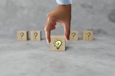 Tahta bloklar, soru işareti ve ampul ikonu. Cevabı bulma kavramı, bir fikir. Beyin fırtınası.