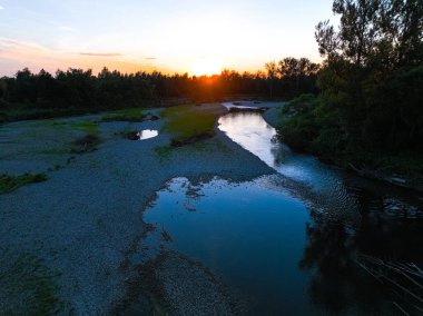 Kayalık nehrin üzerinde güzel bir gün batımı, dağ nehri. 4K 'da bir ormanın ortasında kayalık bir nehir. Gökyüzünü yansıtan sakin nehrin havadan görünüşü, yemyeşil arazi, hava manzarası