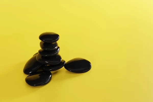 黄色の背景に黒いマッサージ石 マッサージの概念は リラックス Spaと美容ケア 3Dレンダリング 3Dイラスト — ストック写真