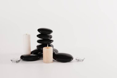 Hafif arka planda siyah masaj taşları ve mumlar. Masaj konsepti, gerçekçilik. Kaplıca ve güzellik hizmeti. 3B görüntüleme, 3B illüstrasyon.