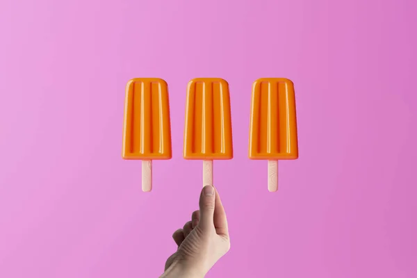 Hand Hält Orangefarbenen Eislutscher Auf Rosa Hintergrund Konzept Sommer Urlaub — Stockfoto