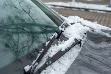A car covered with snow. The onslaught of winter and snow for motorists. Snow on the car, windshield, car mirrors.
