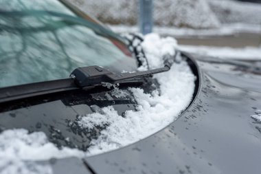 A car covered with snow. The onslaught of winter and snow for motorists. Snow on the car, windshield, car mirrors.