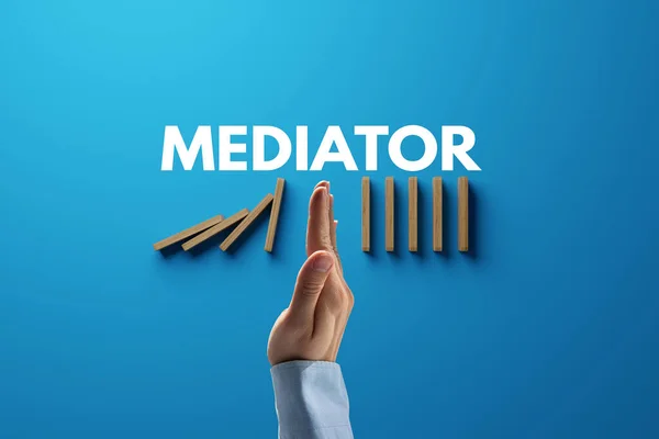 Dominoes falling over, stopped by hand and mediator. The concept of mediation and the use of mediator services. Mediation help for people in problems.