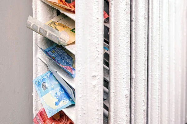 stock image euro banknotes in a central heating radiator, the concept of expensive heating costs, close-up