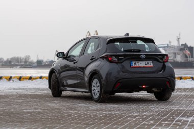Riga, Letonya - 9 Şubat 2021: Metalik gri Toyota Yaris Hybrid Y20 versiyonu Hatchback arabası deniz kenarına park edilmiş.