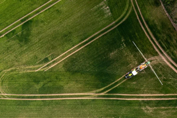 从上往下看拖拉机在大绿地上喷洒化学品 农业概念 — 图库照片