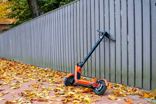 Elektroroller Einem Holzzaun Rand Eines Bürgersteigs Der Mit Herbstblättern Bedeckt — Stockfoto