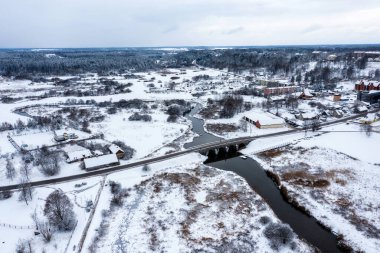 Karlı bir kış gününde Abava nehri üzerinde kemerleri olan eski bir taş köprü, Kandava, hava manzaralı.