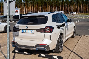Riga, Letonya, 29 Nisan 2022: Süpermarketteki şarj istasyonundaki elektrikli arabalar Tesla Model S ve BMW ix3