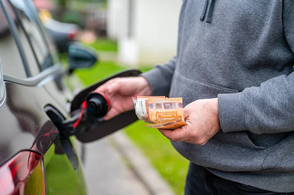 a man s hand counts money while standing at an open fuel tank, the concept of rising fuel prices