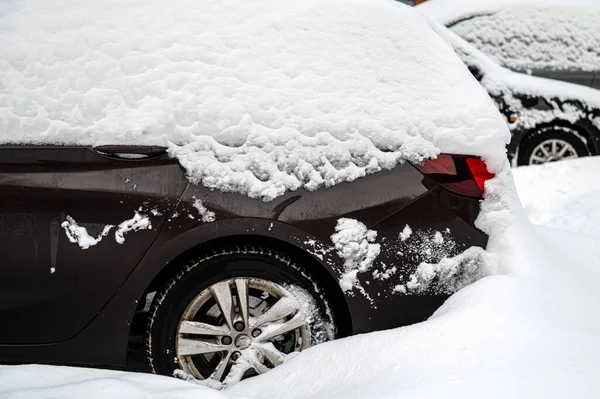 Snow-covered cars in the parking lot in the courtyard of a residential building