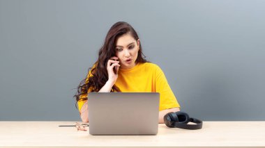 Genç bayan masada oturuyor, çalışırken modern teknolojiyi kullanıyor, online çalışma konsepti