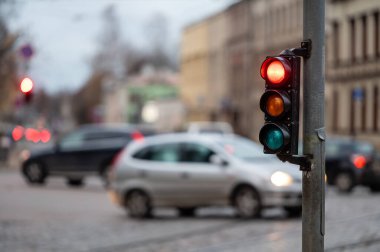 Trafik ışıklarıyla şehir trafiğinin bulanık görüntüsü, ön planda kırmızı ışıklı bir semafor.