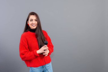 Sunum sırasında kırmızı kazak giyen kadın konferans konuşmacısı dikkat çekmek için gri renkte izole edildi.