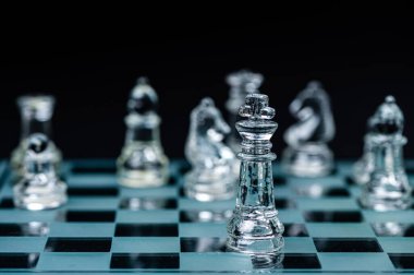 glass chess board game in black background ,selective focus on King, leadership ,winner concept