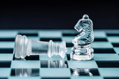 transparent glass chess on dark background, selective focus on knight piece, close-up