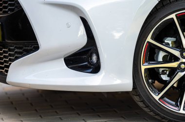 close-up of the wheels and bumpers of a car parked in the yard of a residential house, lower section