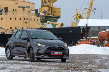 Riga, Letonya - 9 Şubat 2021: Metalik gri Toyota Yaris Hybrid Y20 model araba endüstriyel arka planda