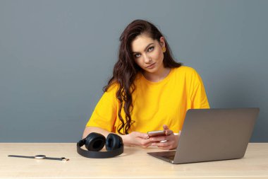 Genç bayan masada oturuyor, çalışırken modern teknolojiyi kullanıyor, online çalışma konsepti