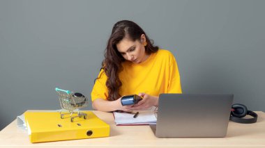 Genç bayan çevrimiçi mağaza müdürü bir masada oturuyor ve bir dizüstü bilgisayar ve belgelerle çalışıyor, online iş konsepti