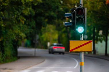 Sonbahar şehrinin kapanmış arka planına yeşil ışık yakılmış trafik semaforu, yakın plan