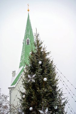 Süslü Noel ağacı ve gökyüzü arka planında kilise çan kulesi, Dobele, Letonya