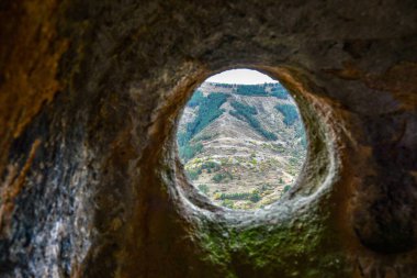 Karşıdaki dağı gören kumtaşı bir mağaranın penceresi. Arkaplana seçici odak